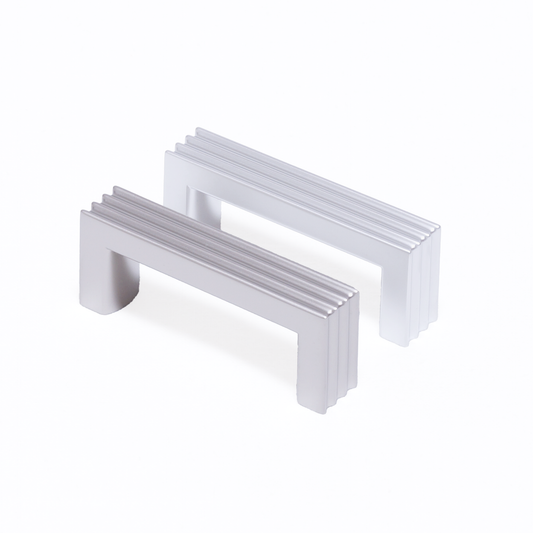 Zwei Design-Bügelgriffe Kamala 64 mm nebeneinander in Nickel matt und Chrom matt galvanisiert auf weißem Hintergrund